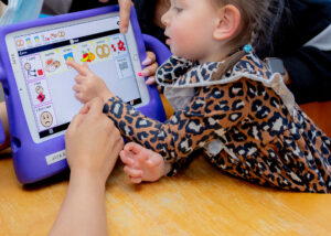 Child using a speech-generating device with therapist support during a communication therapy session