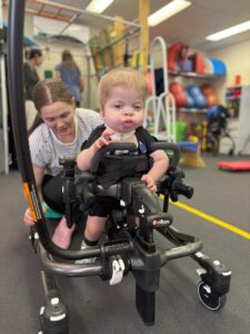 Child using a Rifton gait trainer during a physiotherapy session to support mobility and independence